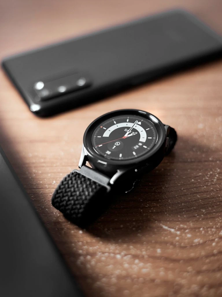 Black smartwatch on a leather strap against a concrete background.